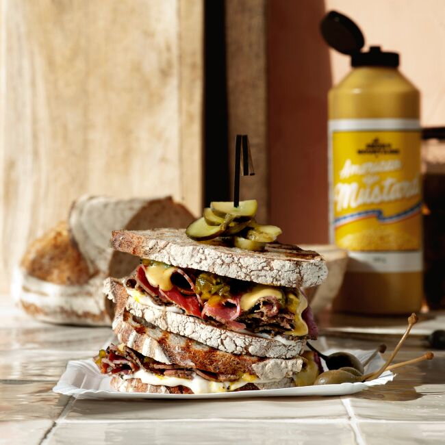 Hoog opgestapelde pastrami sandwich met augurk en Amerikaanse mosterd