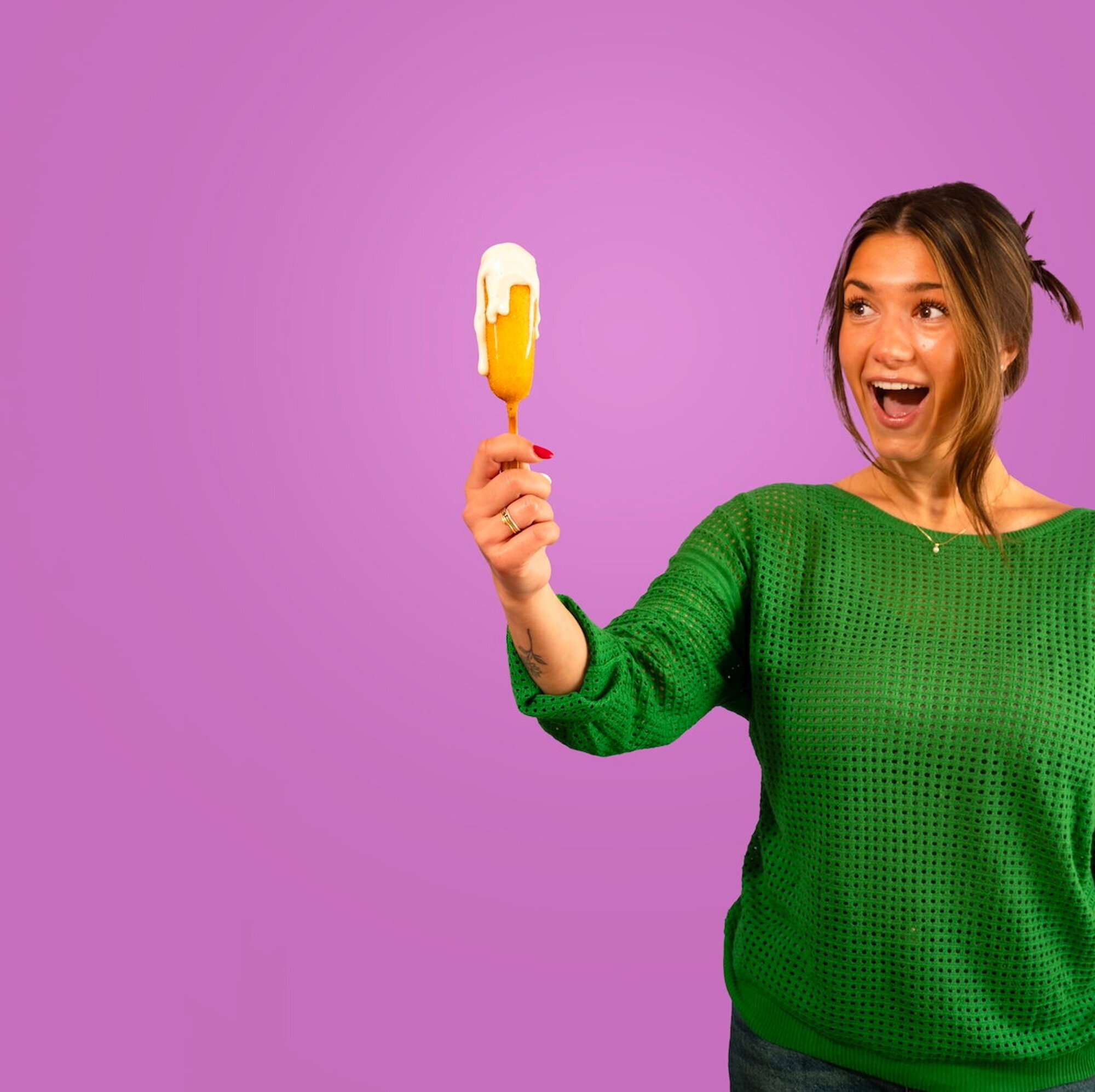 Paarse achtergrond corndog in hand van vrouw
