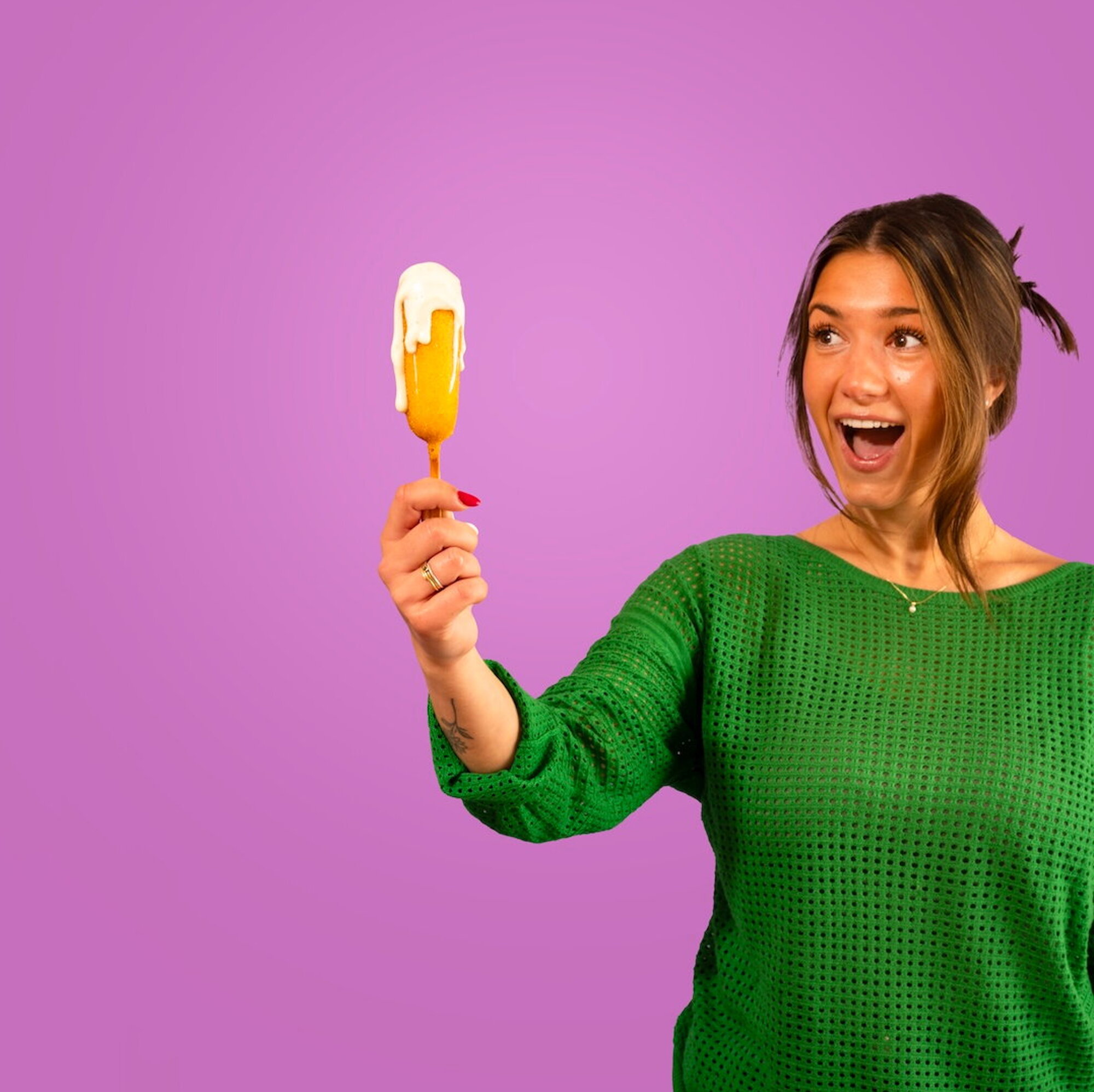 Paarse achtergrond corndog in hand van vrouw