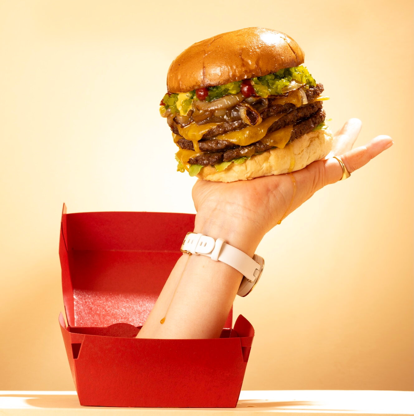 Hand uit rode doos met smashburger erop